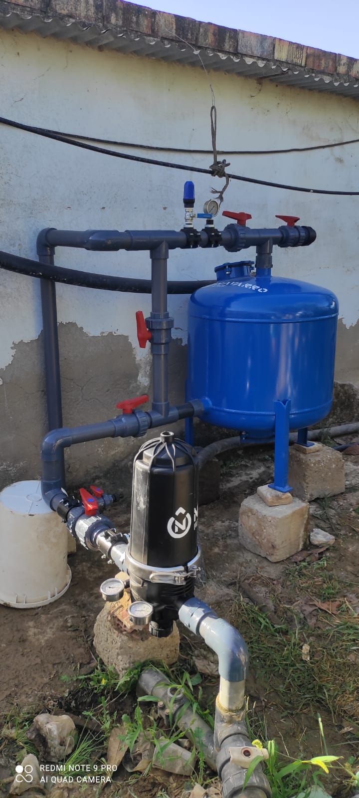 Una bomba de agua está situada al lado de un tanque azul.