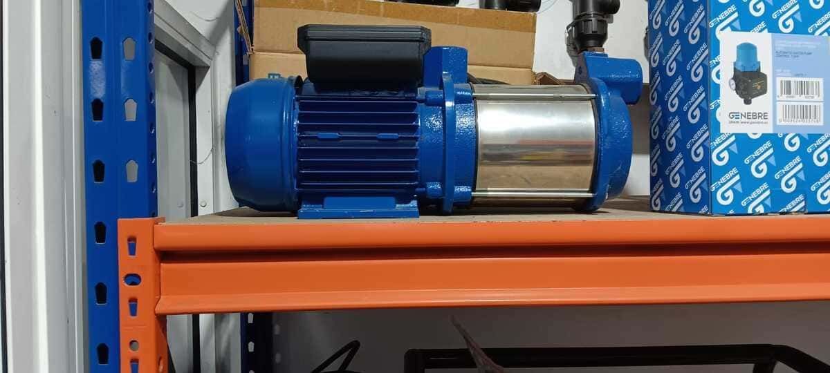 Una bomba de agua azul y plateada está encima de un estante.