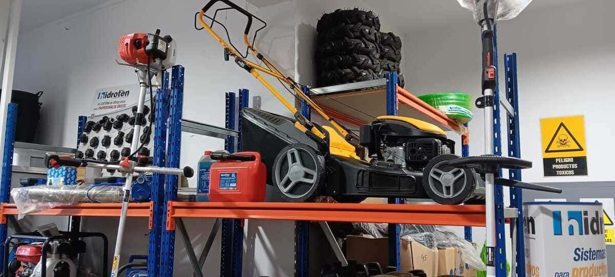 Hay una cortadora de césped encima de un estante en un garaje.