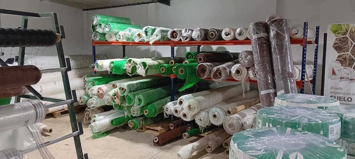 Un almacén lleno de muchos rollos de plástico verdes y blancos.