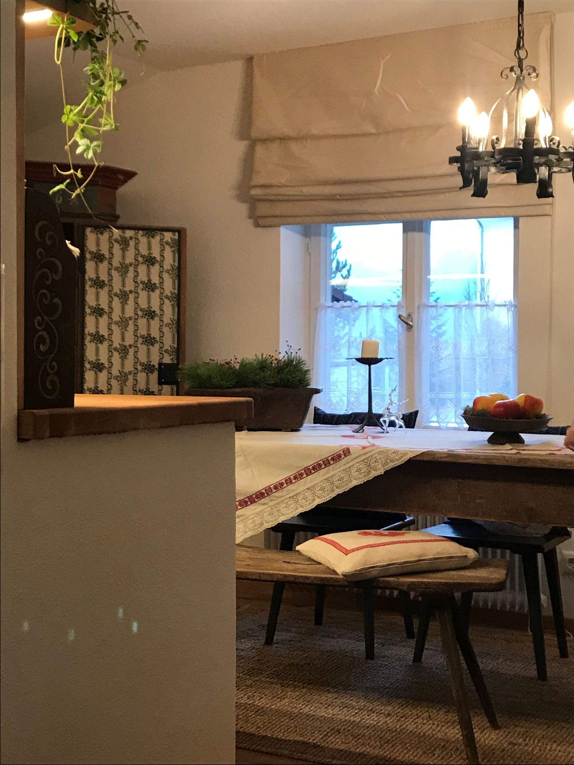 Gemütliches Esszimmer mit Holztisch, Bänken und einem Fenster mit dünnen Vorhängen.