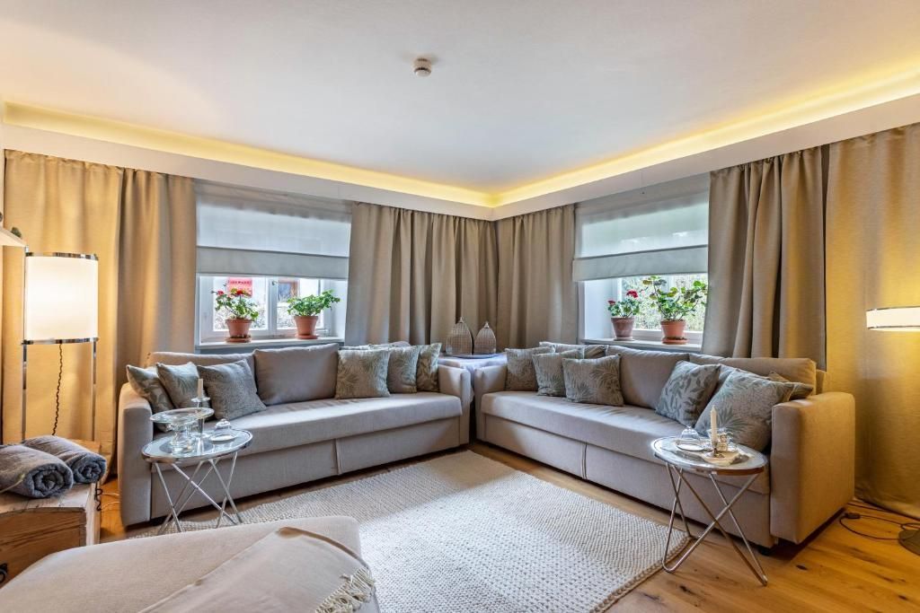 Gemütliches Wohnzimmer mit großem grauen Ecksofa, neutralen Vorhängen und Akzentbeleuchtung.