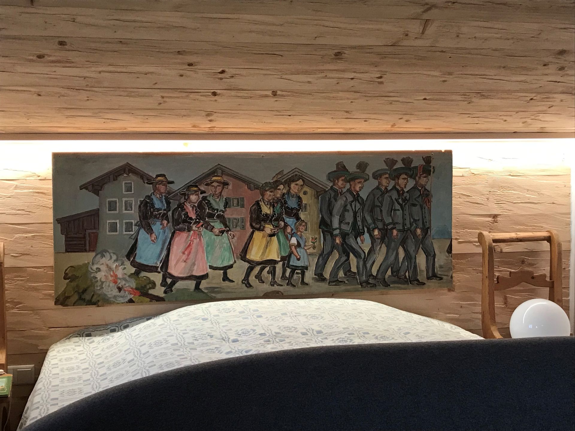 Gemälde von Menschen in Tracht, die an Häusern vorbeigehen, über einem Bett.