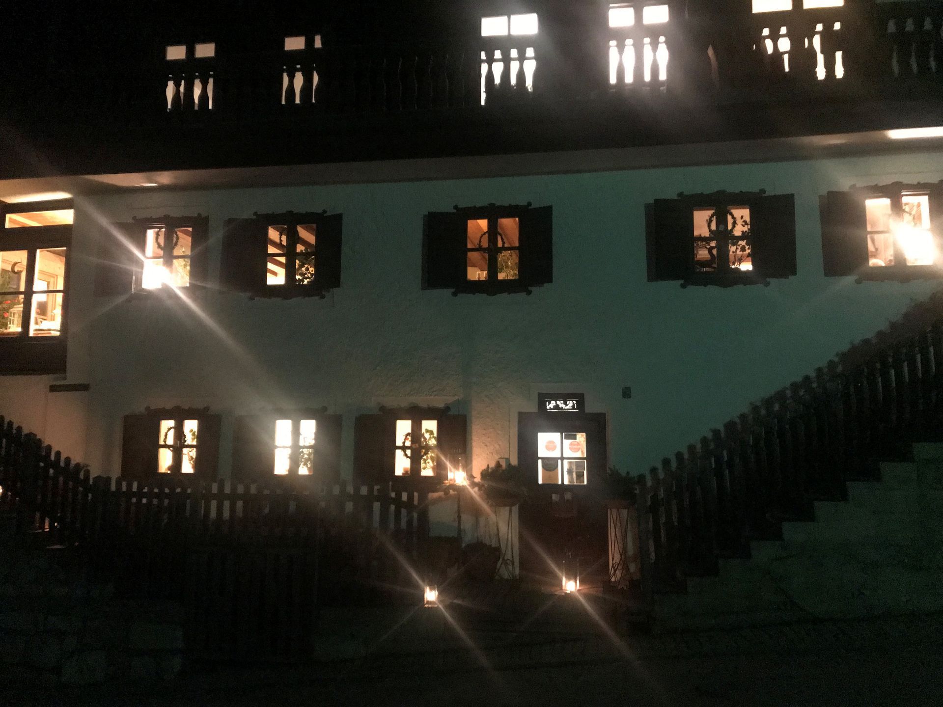 Biohotel Kurz bei Nacht mit beleuchteten Fenstern, einer Holztreppe und einem Holzzaun.