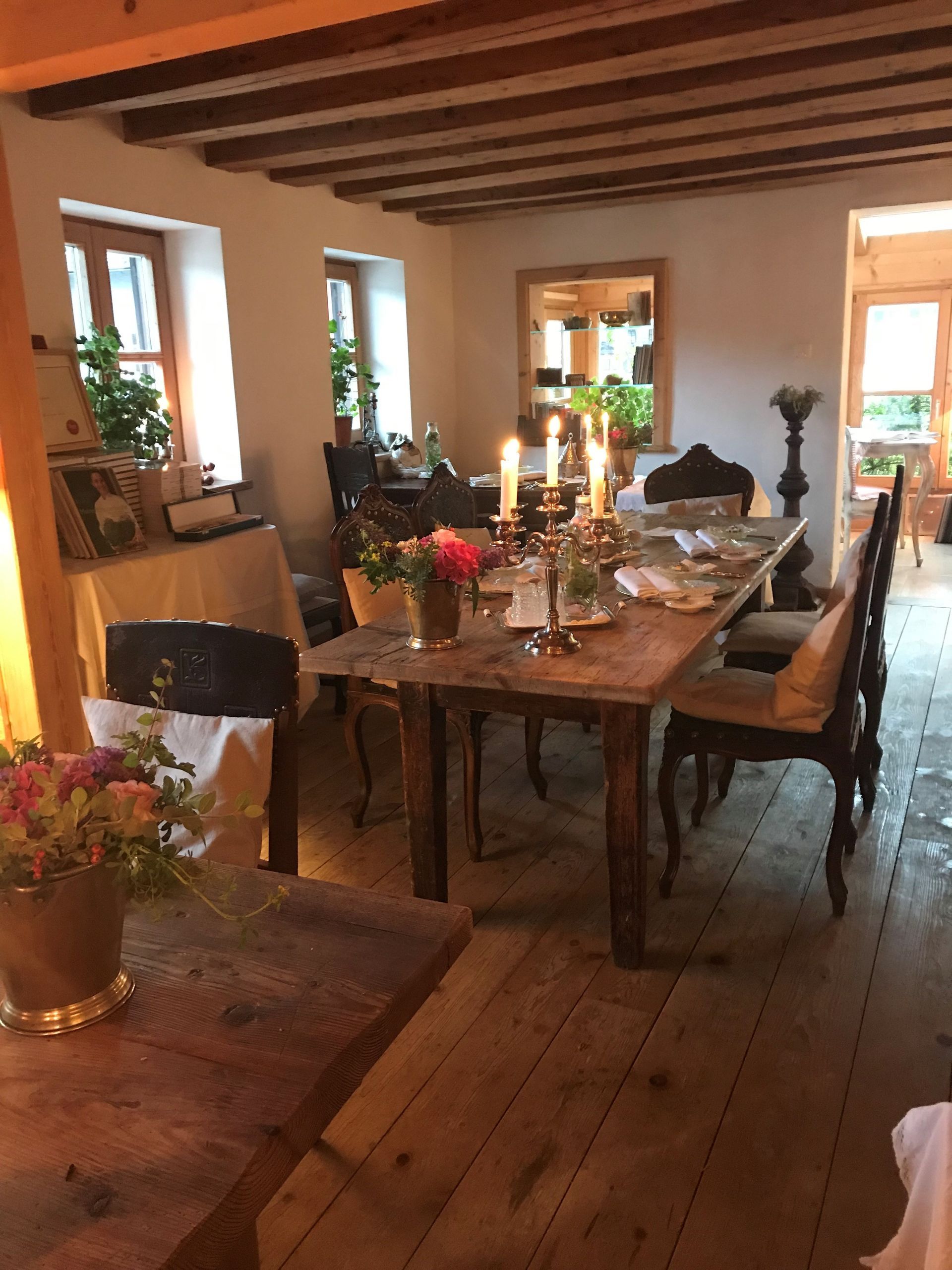 Esszimmer mit Kerzen, Blumen und Holzmöbeln.