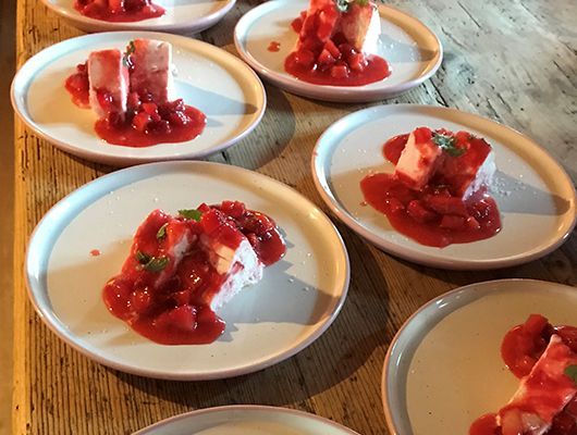 Dessertteller: weiße Blöcke mit Erdbeersoße auf cremefarbenen Tellern, Holztisch.