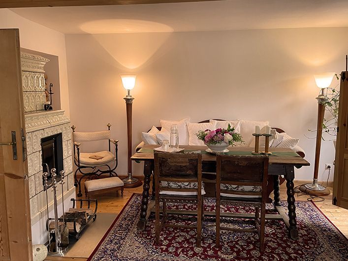 Gemütliches Esszimmer mit antikem Tisch und Stühlen, Sofa, Kamin und zwei Lampen.