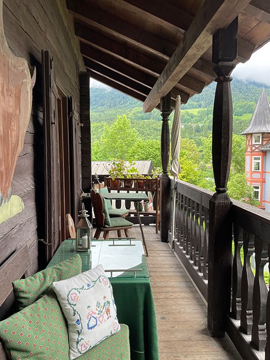 Holzbalkon mit Blick auf eine Berglandschaft, ausgestattet mit Tisch und Stühlen.