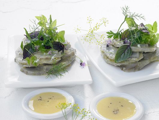 Wilde und kultivierte Kräuter auf warm marinierten Artischockenböden mit Senfsauce.