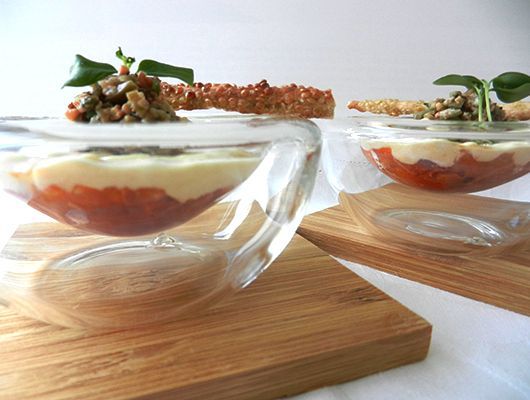 Zweischichtige Vorspeisen in durchsichtigen Glasschalen auf Holzbrettern.