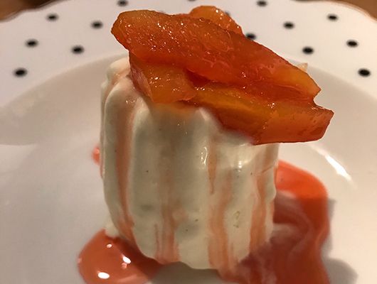 Quitten mit Honig karamellisiert, zu zartschmelzendem Vanilleparfait auf einem Teller mit Tupfen.