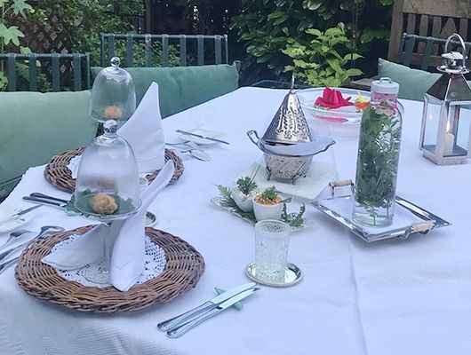 Esstischset für den Außenbereich mit eleganter Dekoration und Gedecken.