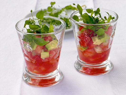 Zwei Glasbecher gefüllt mit Wassermelone, Avocado und Blattgemüse.