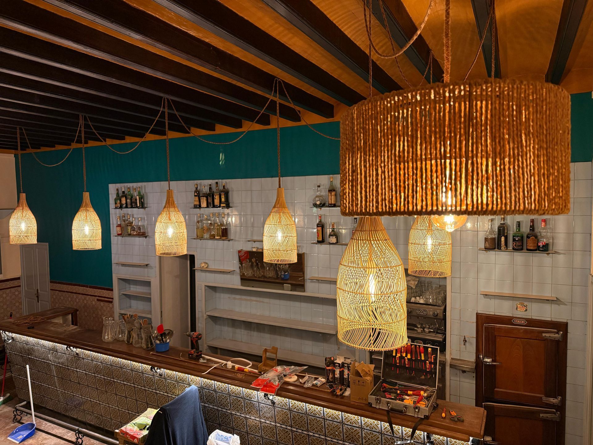 Interior de un bar con techo y barra de madera. Lámparas de ratán cuelgan sobre la barra.