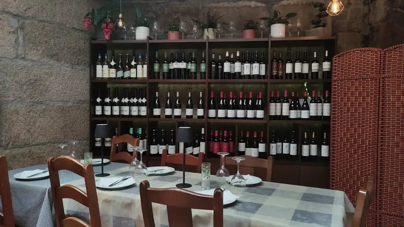Interior de restaurante con una mesa puesta para los comensales y un gran botellero en la pared.