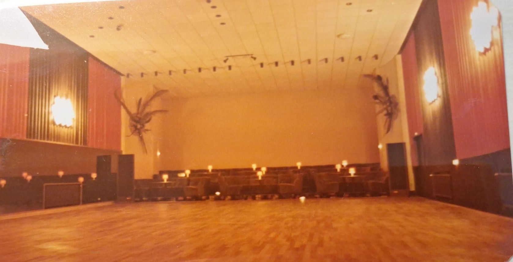 Ein großer leerer Raum mit Holzboden und einer Bühne.