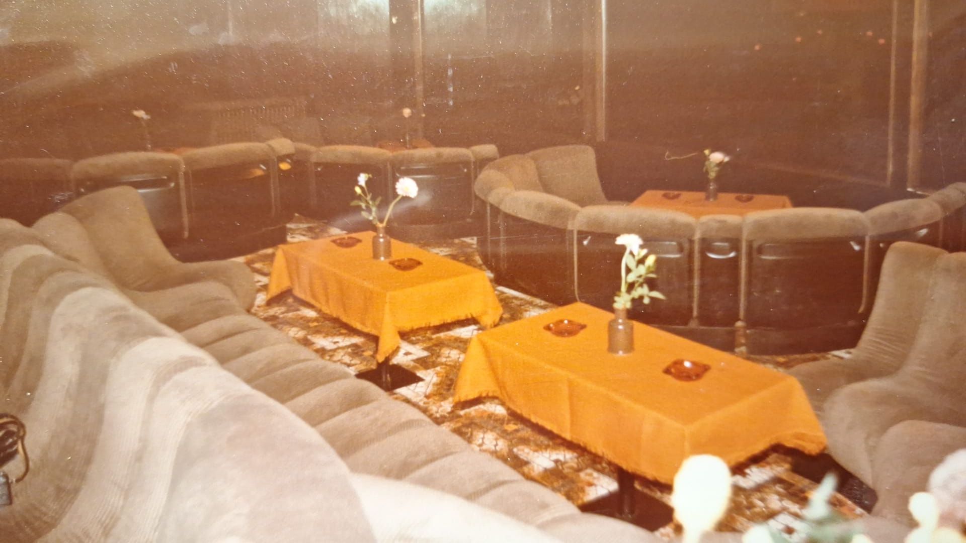 Ein Raum mit vielen Sofas und Tischen mit Blumen darauf.