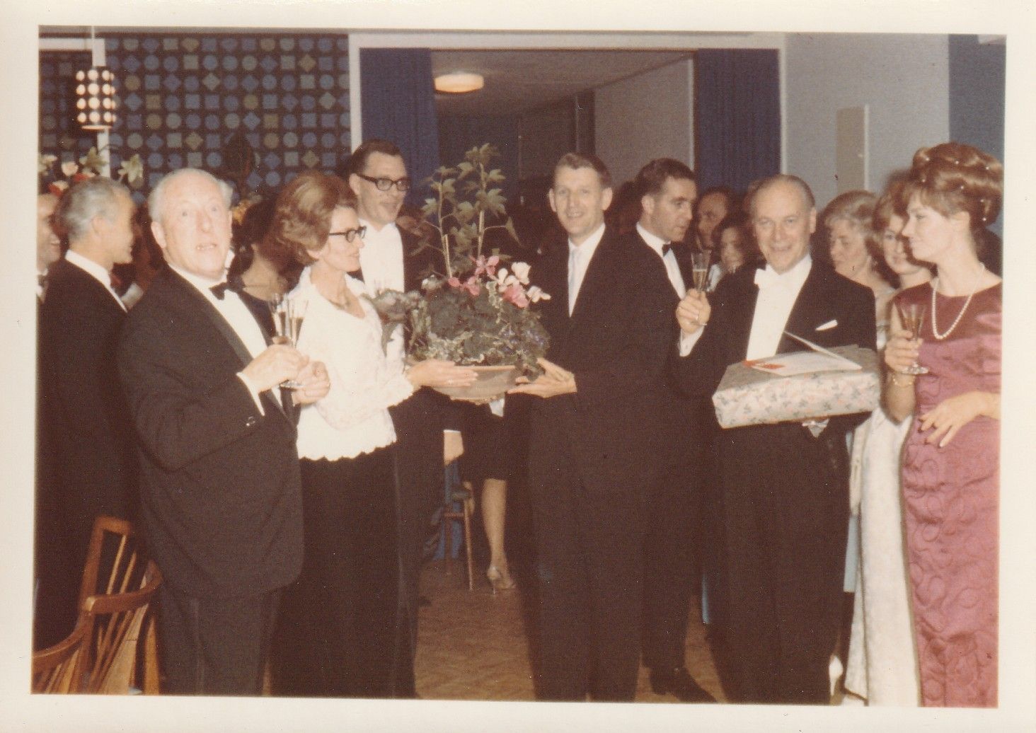 Ein Mann im Smoking gibt einer Frau einen Blumenstrauß