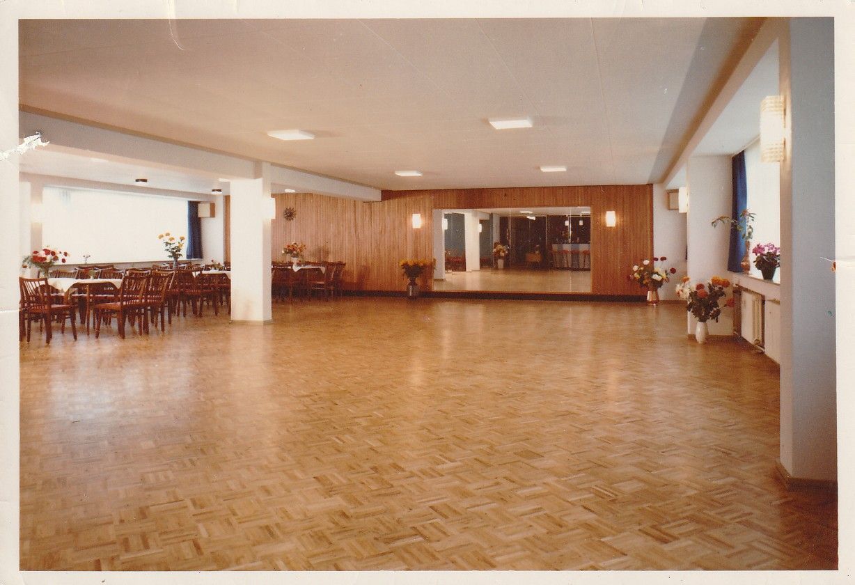 Ein großer leerer Raum mit Holzboden und Tischen und Stühlen