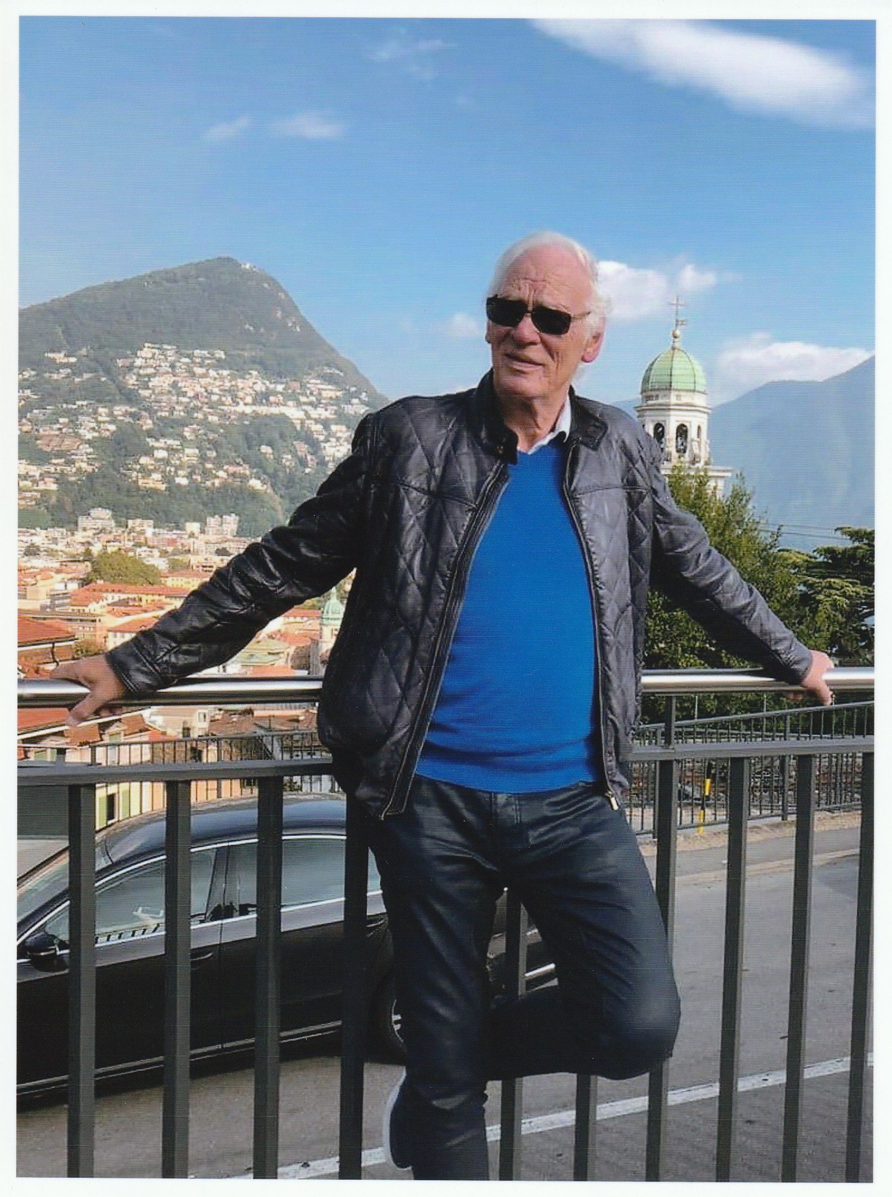 Ein Mann in einem blauen Pullover lehnt an einem Geländer.