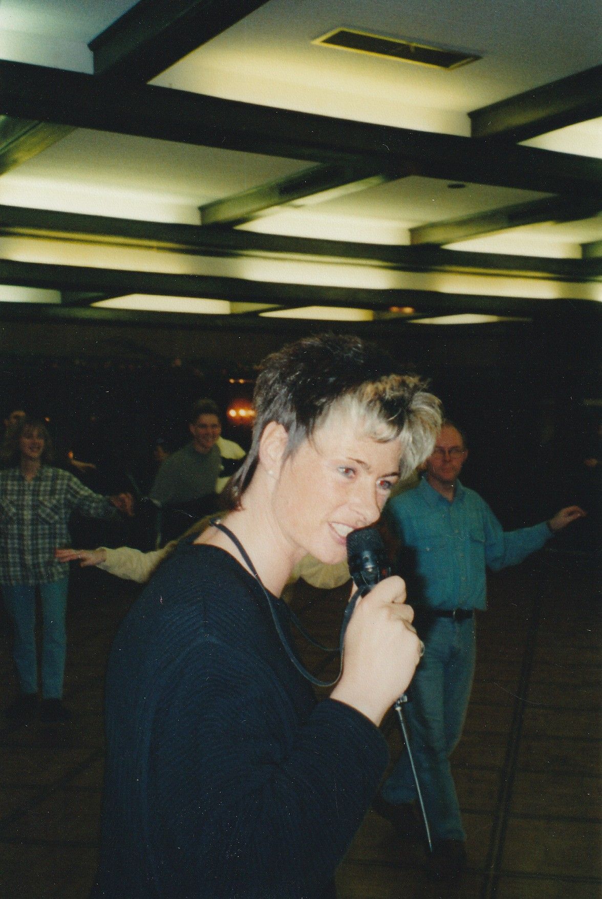 Eine Frau singt in einem dunklen Raum in ein Mikrofon