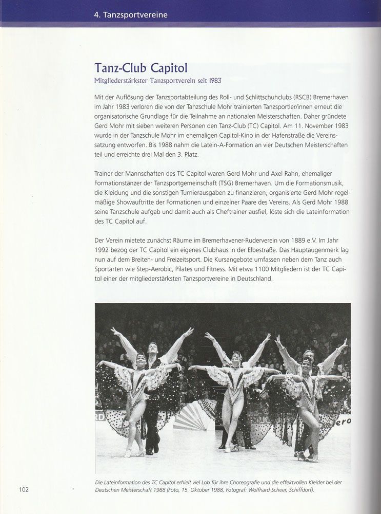 In einem Buch ist eine Seite aufgeschlagen, auf der eine Gruppe tanzender Menschen abgebildet ist.