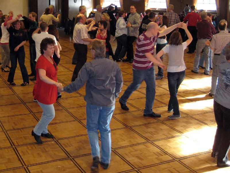 Eine Gruppe von Menschen tanzt auf einem Holzboden