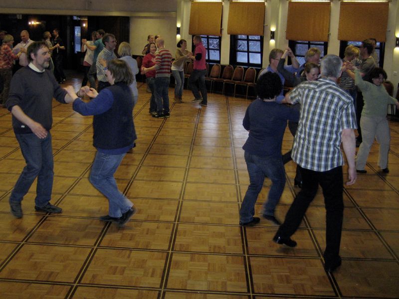Eine Gruppe von Menschen tanzt auf einem Holzboden