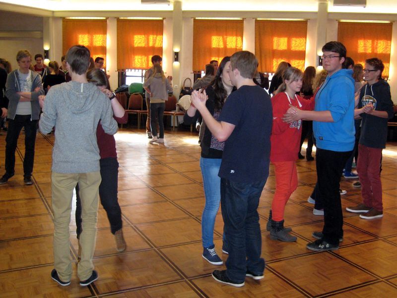 Eine Gruppe junger Leute tanzt in einem großen Raum