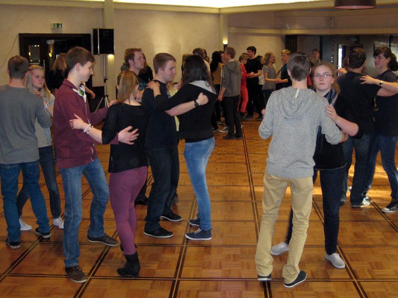 Eine Gruppe von Menschen tanzt auf einem Holzboden