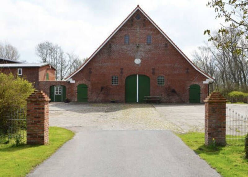 Eine gemauerte Scheune mit grünen Türen und einer Auffahrt, die dorthin führt