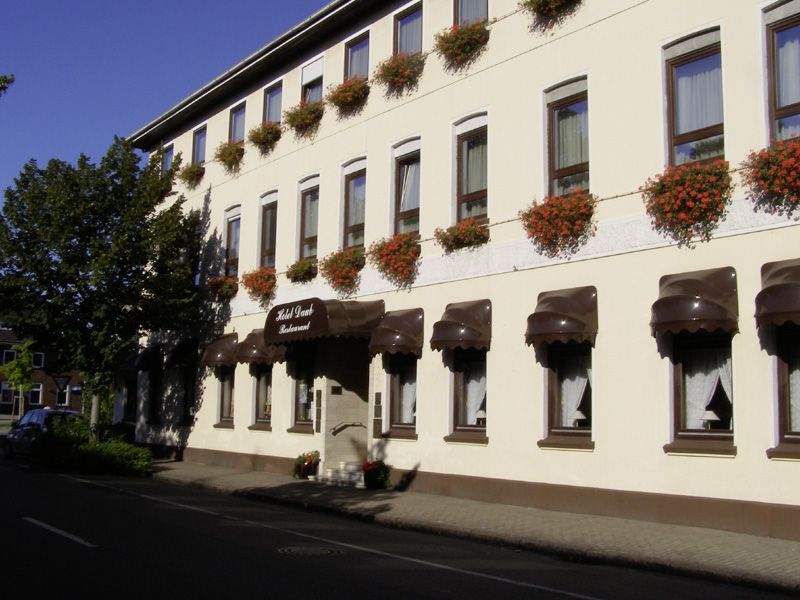 Ein weißes Gebäude mit braunen Markisen und Blumen an den Fenstern