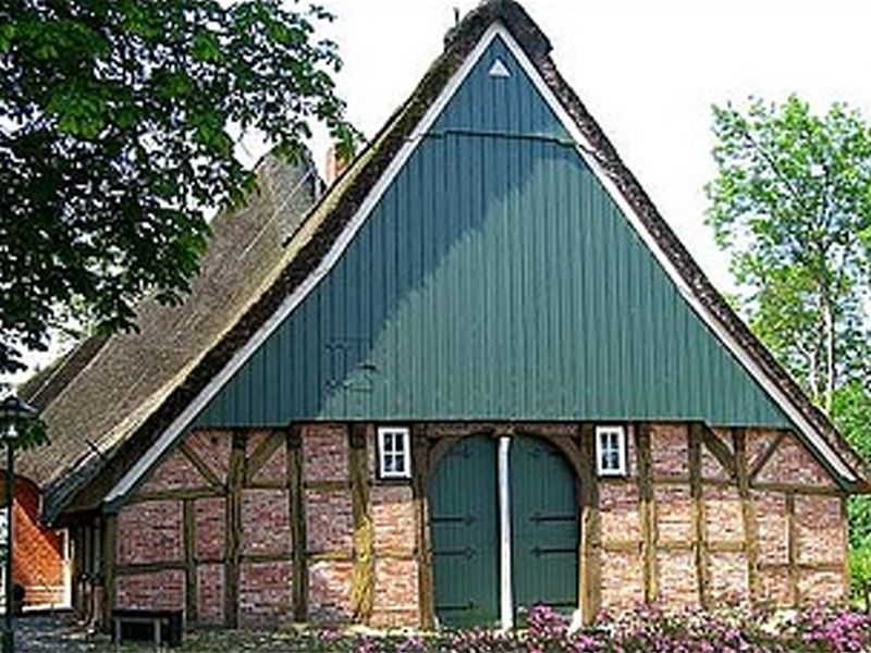 Ein Backsteingebäude mit einem grünen Strohdach