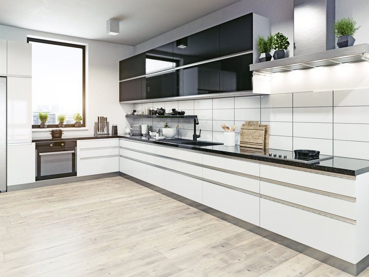 Una cocina moderna con gabinetes en blanco y negro y piso de madera.