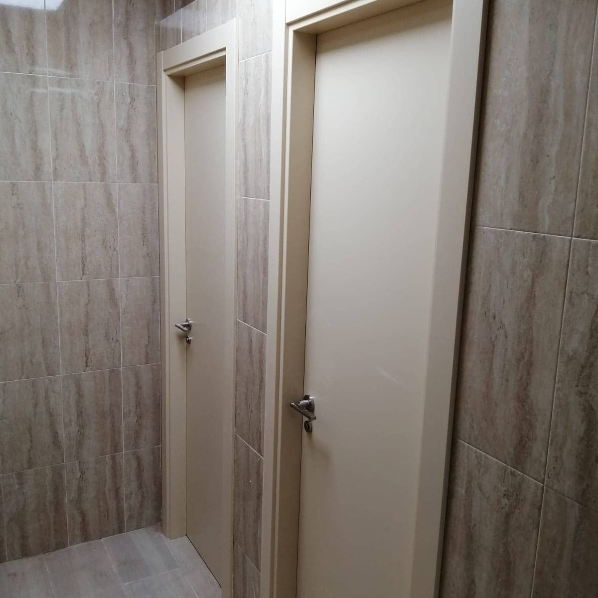 Un pasillo con dos puertas blancas y paredes de azulejos.