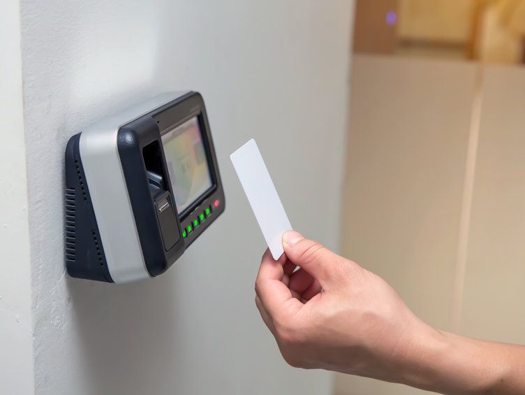 Una persona sostiene una tarjeta frente a un escáner de huellas dactilares.