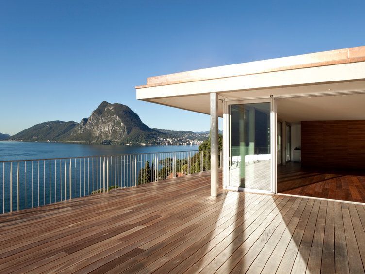 Una terraza de madera con vistas a un lago y a las montañas.