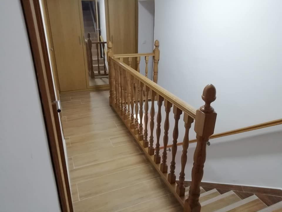 Un pasillo con escaleras y barandilla de madera.