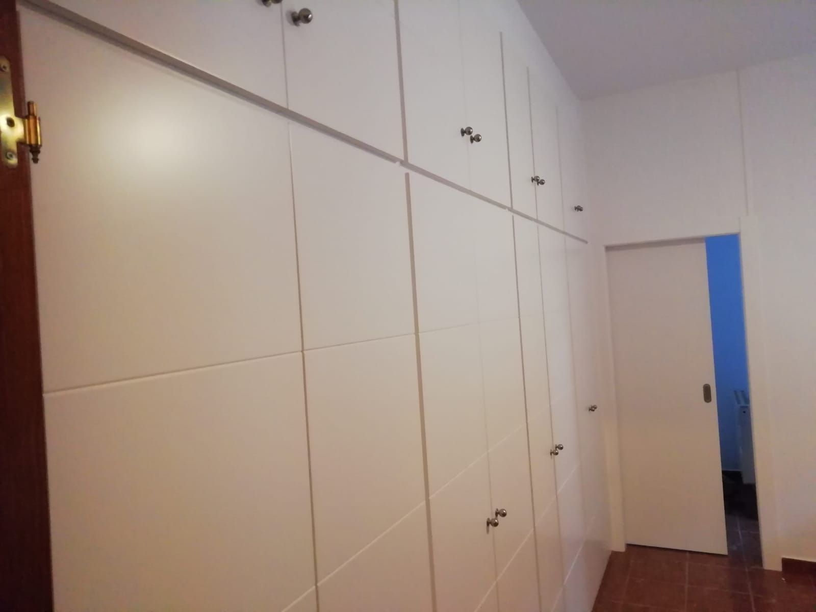 Un pasillo con armarios blancos y una puerta corrediza.