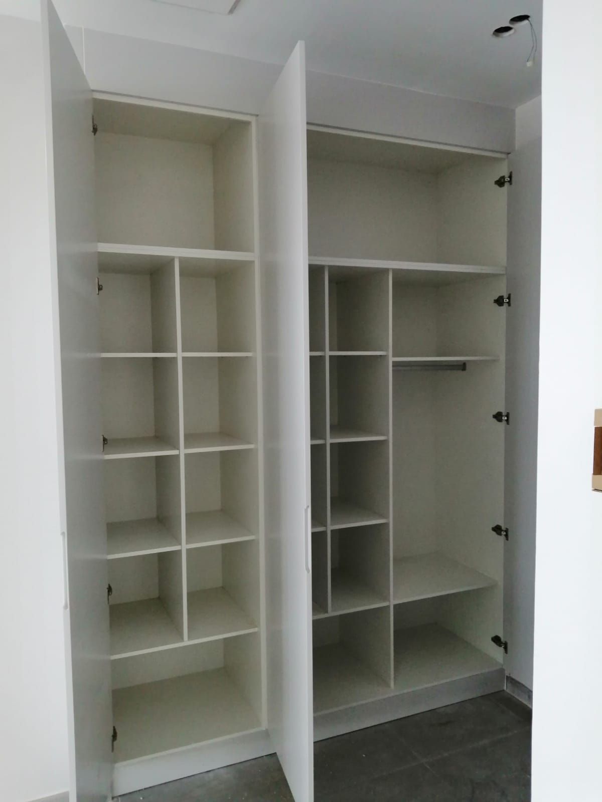 Un armario blanco con las puertas abiertas y estantes.