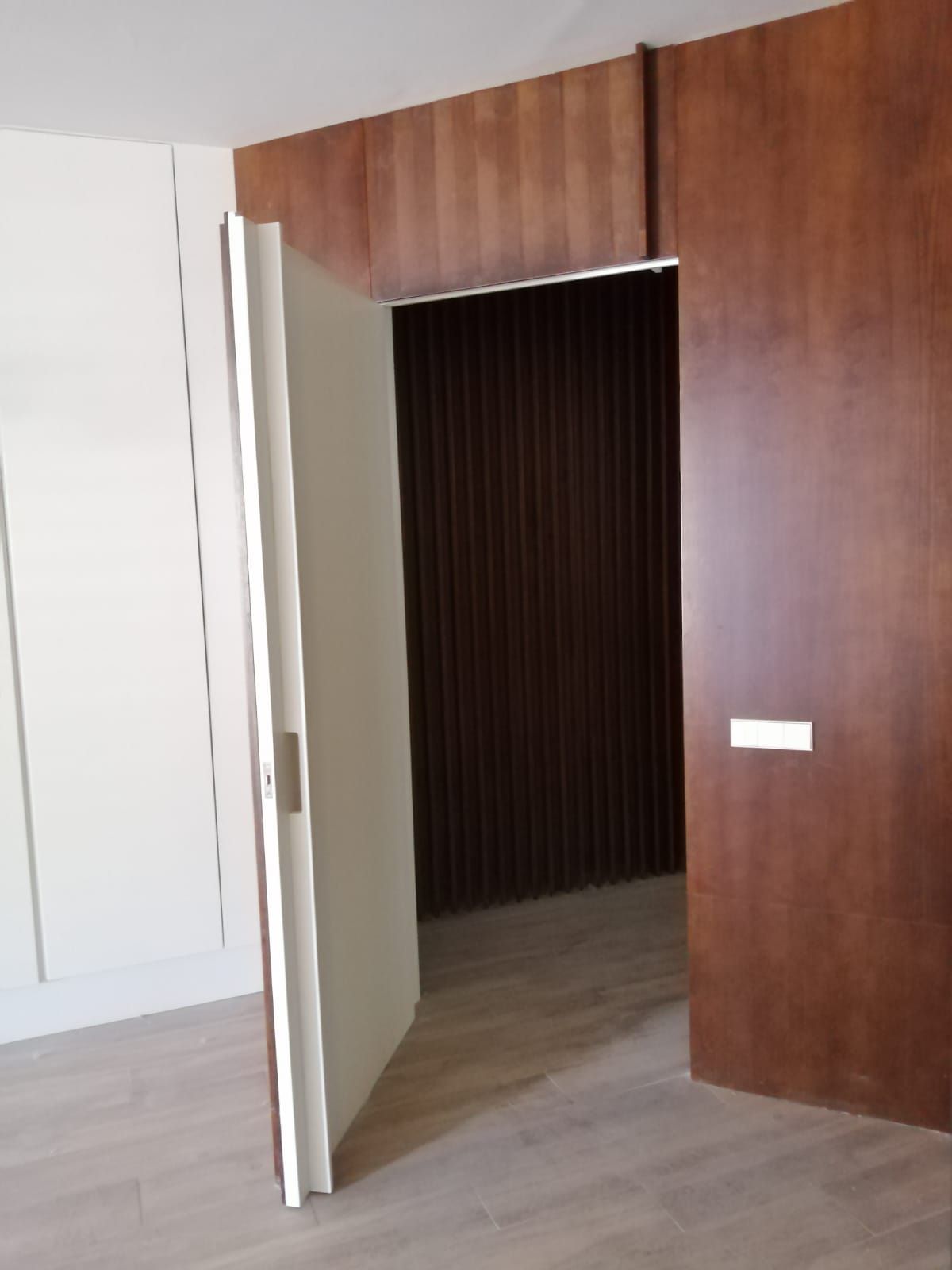 Una habitación con una pared de madera y una puerta blanca.