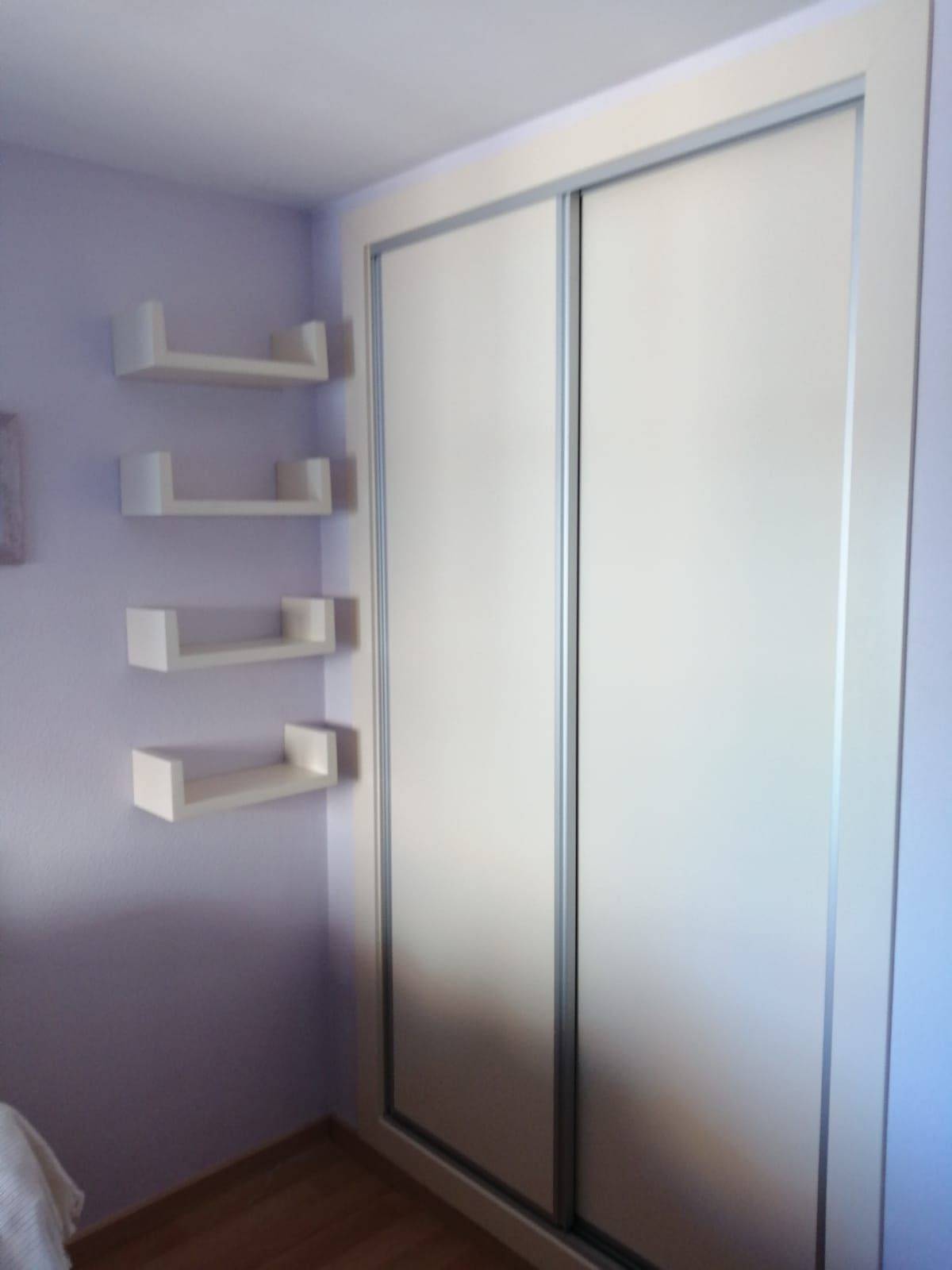 Un dormitorio con paredes moradas y estantes blancos.