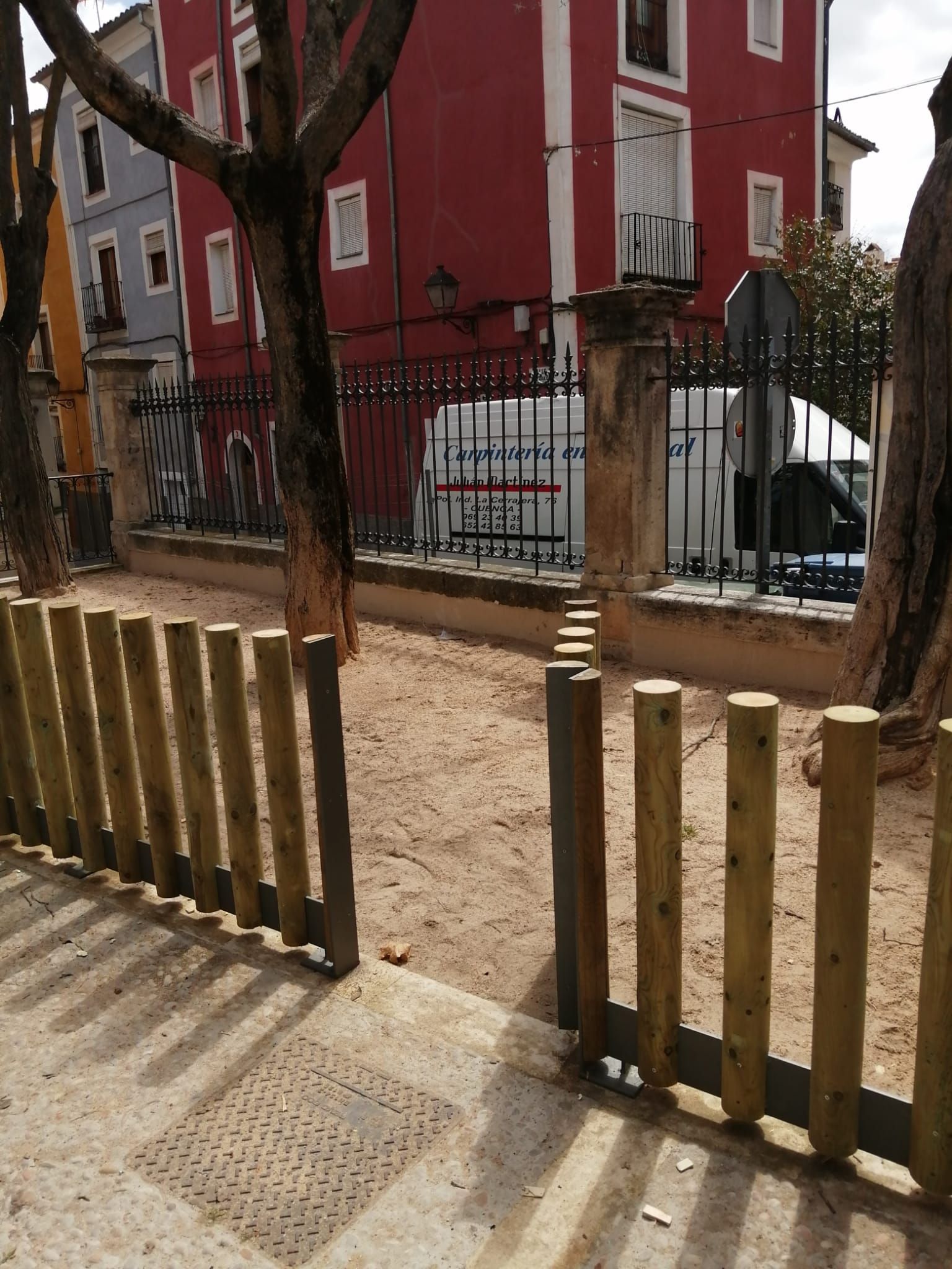 Una valla de madera con un edificio rojo al fondo.
