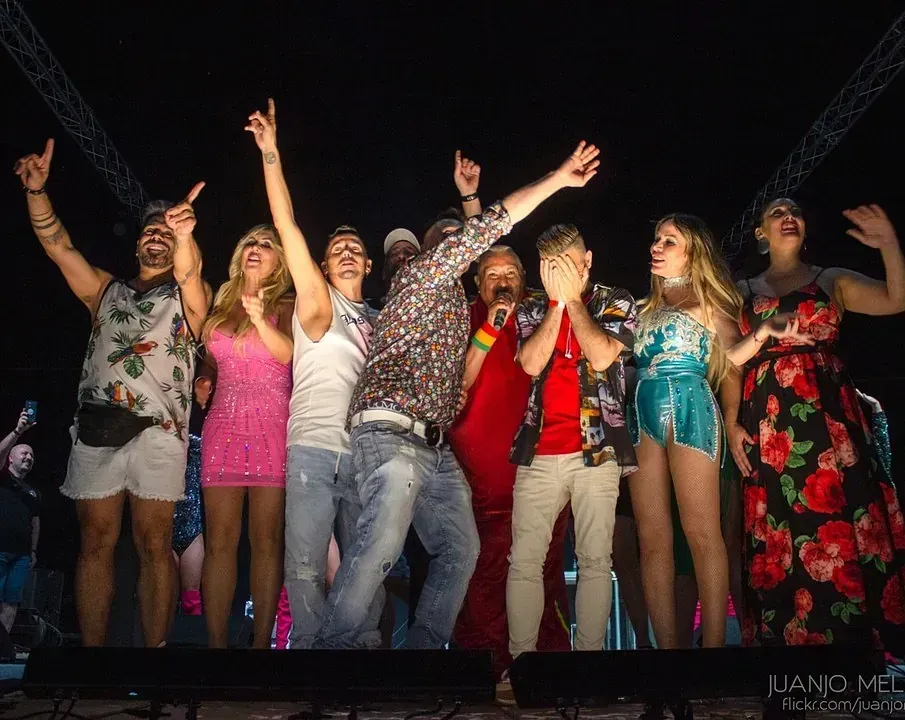 Un grupo de personas en el escenario, celebrando con los brazos en alto en un evento nocturno.