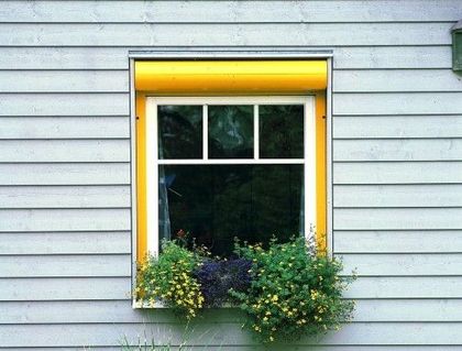 Ein Fenster mit einem gelben Rahmen und Blumen darin