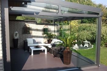 Eine Terrasse mit Sofa, Stühlen, Tisch und Topfpflanzen.