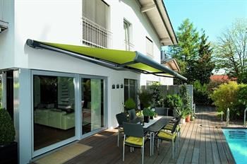 Eine Terrasse mit Tisch und Stühlen unter einer Markise neben einem Pool.