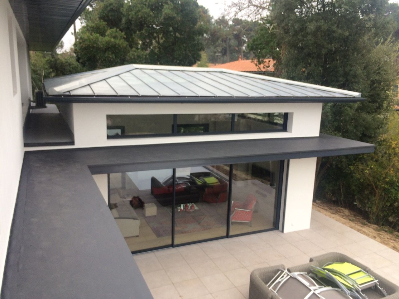 Maison avec de grandes vitres et une toiture en zinc