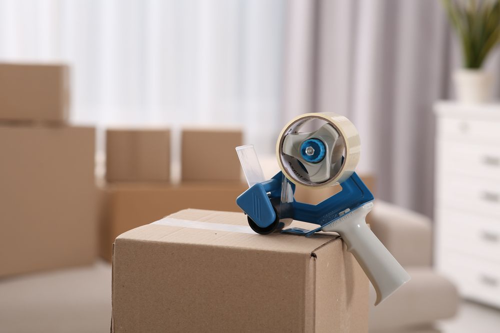 Un dispensador de cinta está colocado encima de una caja de cartón.