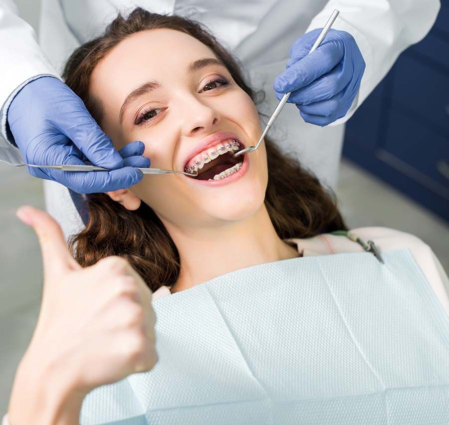 Dentista examinando los dientes de un paciente sonriente con instrumental dental en una clínica.